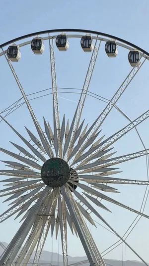 Ferris wheel with starburst design against clear blue sky.