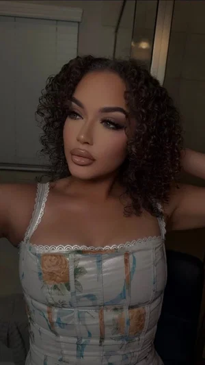 Woman with curly hair in floral corset top, indoors, posing for camera.