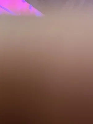 Blurred image with pink and purple lighting, no clear person or object visible.