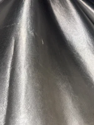 Close-up of shiny silver fabric with folds and light reflections.