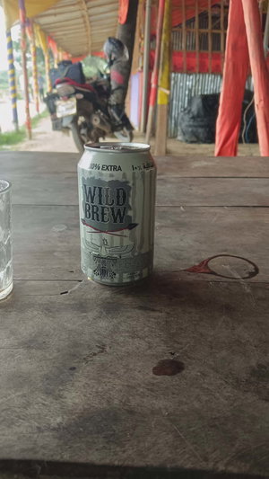 A can of Wild Brew beer sits on a wooden table outdoors.
