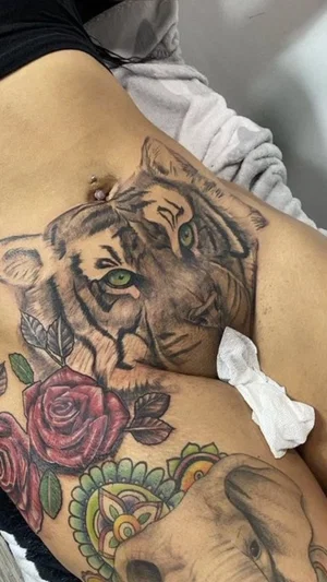 Woman with detailed tattoos on torso, wearing black top, lying down.