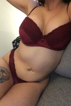 Woman in maroon lace bra and panties on couch.