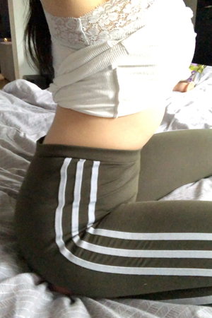 Woman in white lace top and green striped leggings on bed