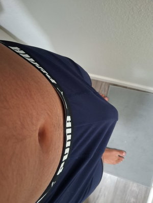 Person in navy underwear showing lower abdomen and feet indoors.