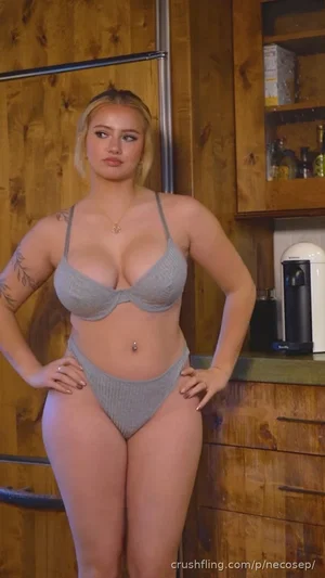 Woman in gray lingerie posing in a wooden kitchen.