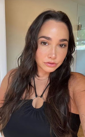 Brunette woman in black halter top taking indoor selfie.