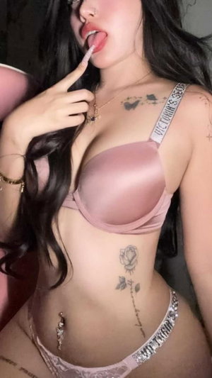 Asian woman in pink lingerie with tattoos taking a selfie.