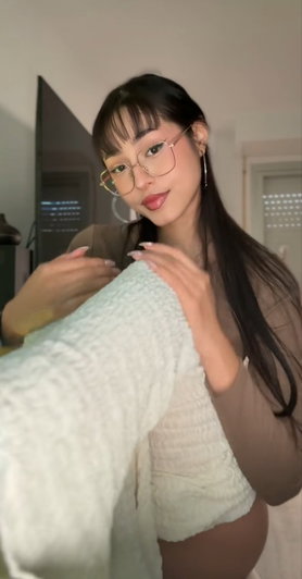 Woman with glasses and long dark hair in sheer top indoors