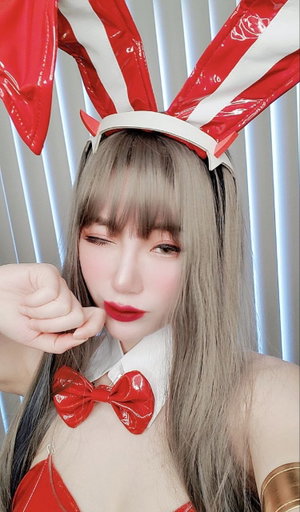 Woman with gray hair wearing red bunny ears and bow tie, posing indoors.