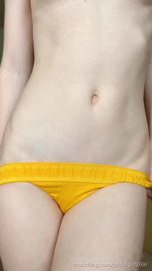 Woman in yellow underwear, showing midriff and hips, indoor setting.