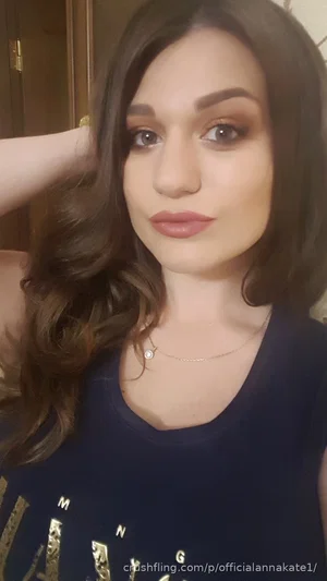 Woman with long brown hair wearing dark blue top, indoors, facing camera.