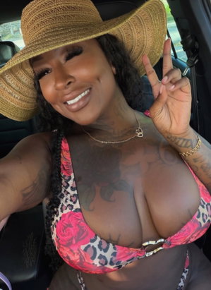 Curvy woman in bikini top and straw hat taking car selfie.
