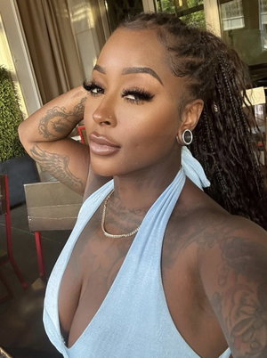 Tattooed woman in blue halter top posing indoors.