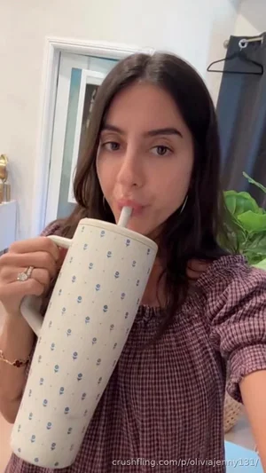 Woman with dark hair in a checkered top sipping from a patterned mug indoors.