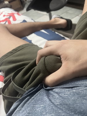 Man in green shorts sitting indoors with hand on lap.