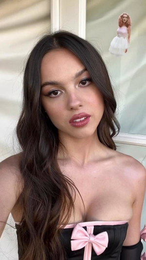 Woman with long dark hair in black strapless top with pink bow.