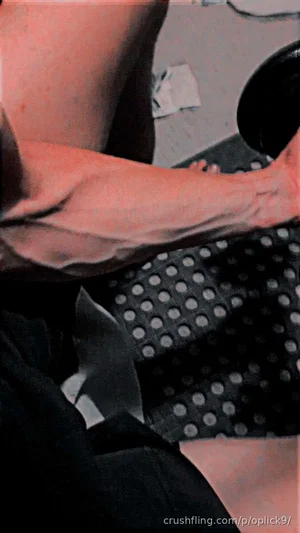 Person with bare legs and arm, wearing black clothing, sitting on patterned mat indoors.