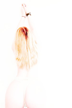 Blonde woman from back with hands raised, wearing white thong, overexposed lighting.