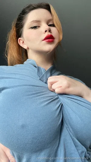 Woman with red lips and styled hair wearing a blue top, posing indoors.