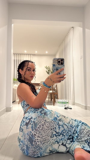 Woman in blue patterned outfit taking mirror selfie in bright indoor space.