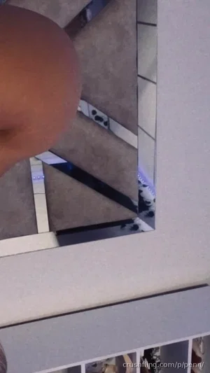 Close-up of a person's bare buttock in a room with tiled floor and mirror reflection.