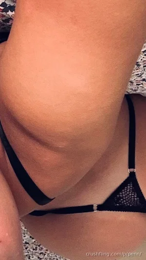 Woman in black lace lingerie, close-up of torso and hip, indoor setting.
