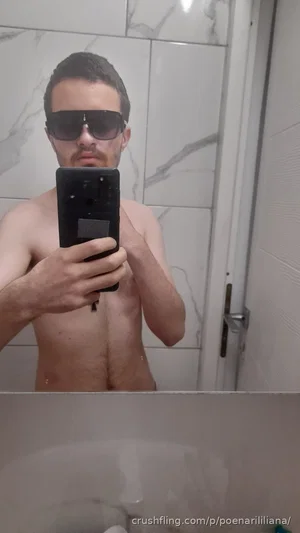 Shirtless man with sunglasses taking mirror selfie in bathroom, chest and arms visible.