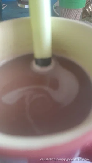 Close-up of a yellow cup with a straw stirring a brown liquid.