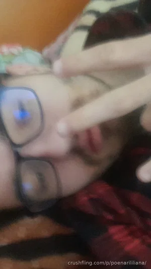 Person with glasses lying down, hand near face, wearing patterned clothing indoors.