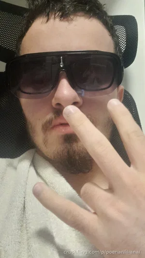 Man with beard and sunglasses making hand gesture, wearing white robe, indoors.
