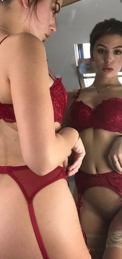 Woman in red lingerie posing before mirror with reflection