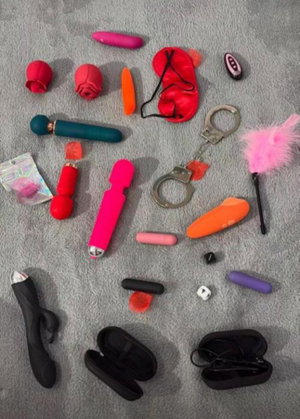 Assortment of adult toys laid out on gray surface.