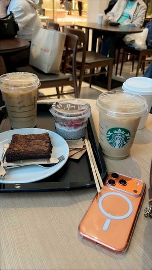 Starbucks drinks and brownie on cafe table with phone.