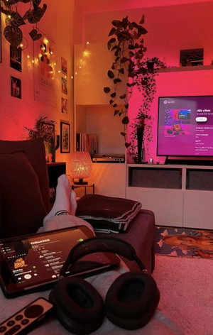 Person's legs on couch in plant-filled living room with lights.