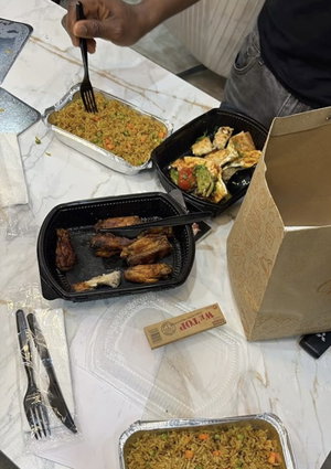 Person eating takeout food at a marble table with containers and utensils.
