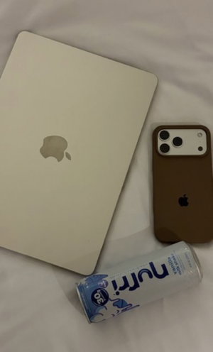 White laptop, brown phone, and Nutri-Go can on white sheets.