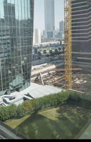 Cityscape with tall buildings, construction site, and green lawn in foreground.