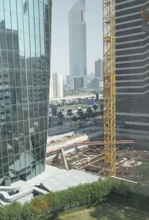 Cityscape with tall glass buildings, construction site, and yellow crane.