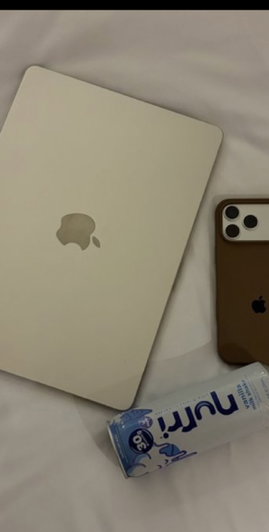 White laptop, brown phone, and Nutri-Go tube on white sheets.