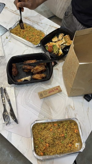 Person eating takeout food at a marble table with containers and utensils.