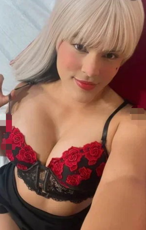 Blonde woman in red lace bra taking indoor selfie.