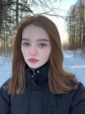 Red-haired woman in black jacket outdoors in snow.