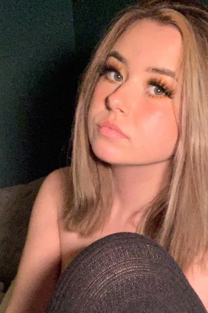 Blonde woman with makeup taking a selfie indoors.