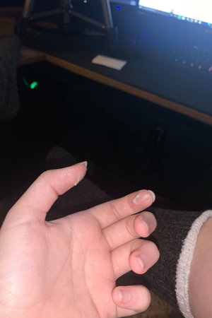 Hand with white nails near computer desk.