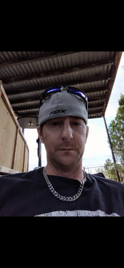 Man in cap and sunglasses taking outdoor selfie.