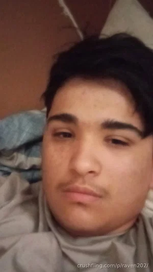 Young man with dark hair lying in bed, wearing a gray turtleneck.