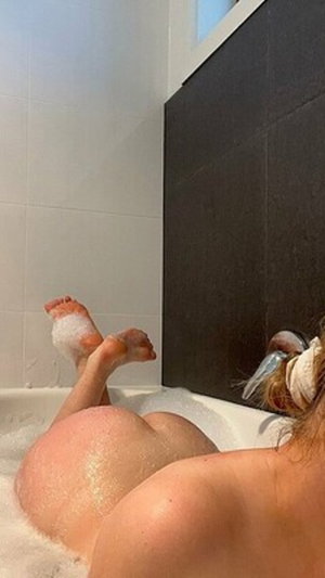 Curvy woman in bubble bath, bare back and buttocks.