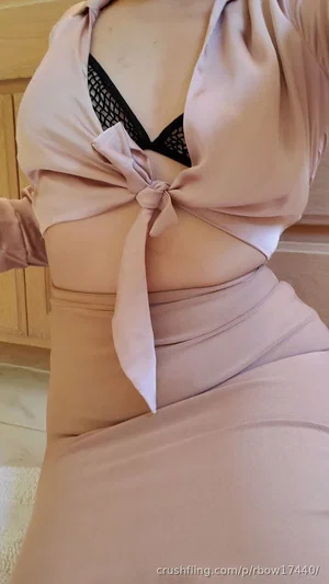 Woman in pink wrap top and black lace bra, standing indoors.