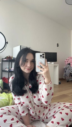 Woman with black hair in heart pajamas on bedroom floor.